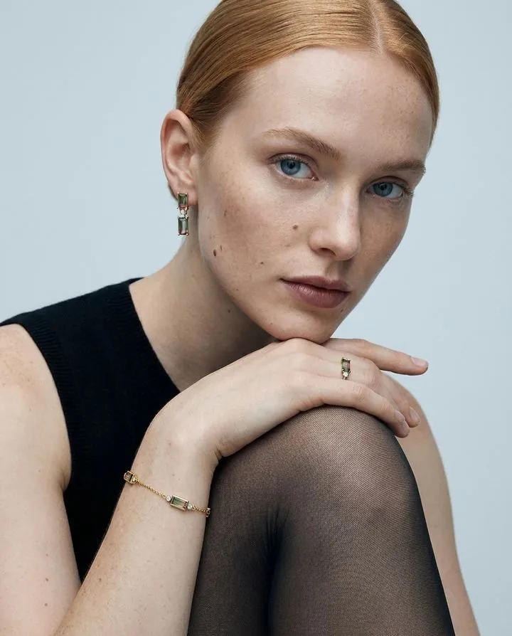 Beauty portrait with a delicate gold ring and bracelet, model in black