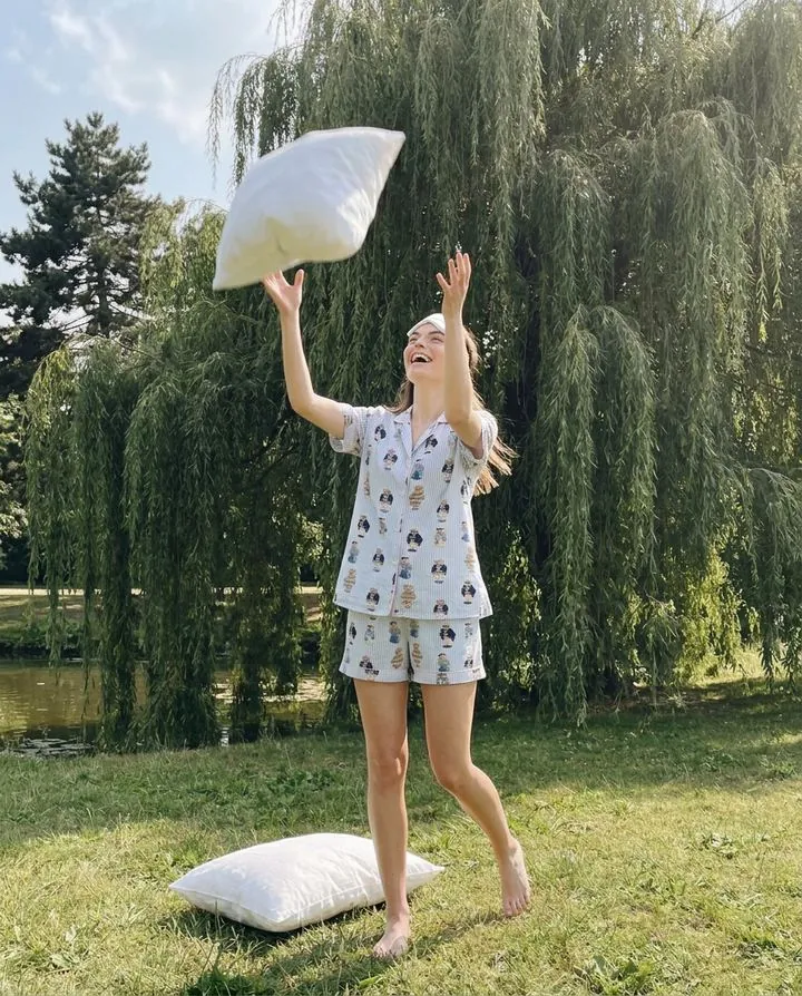 Model tossing a pillow in printed short pajamas under a willow tree